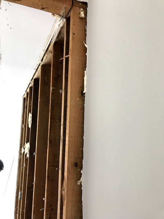 Wooden door frame with visible studs and white drywall, revealing construction.