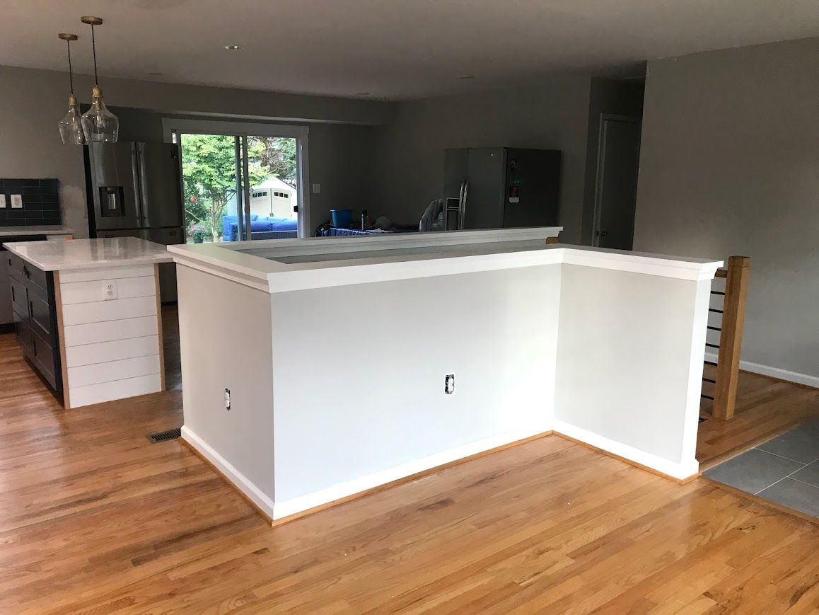 Kitchen with white cabinets, island, and hardwood floors. Gray wall and sliding glass doors visible.