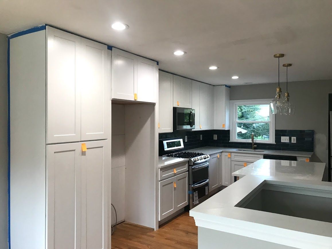 Newly renovated kitchen with white cabinets, gray countertops, and stainless steel appliances.
