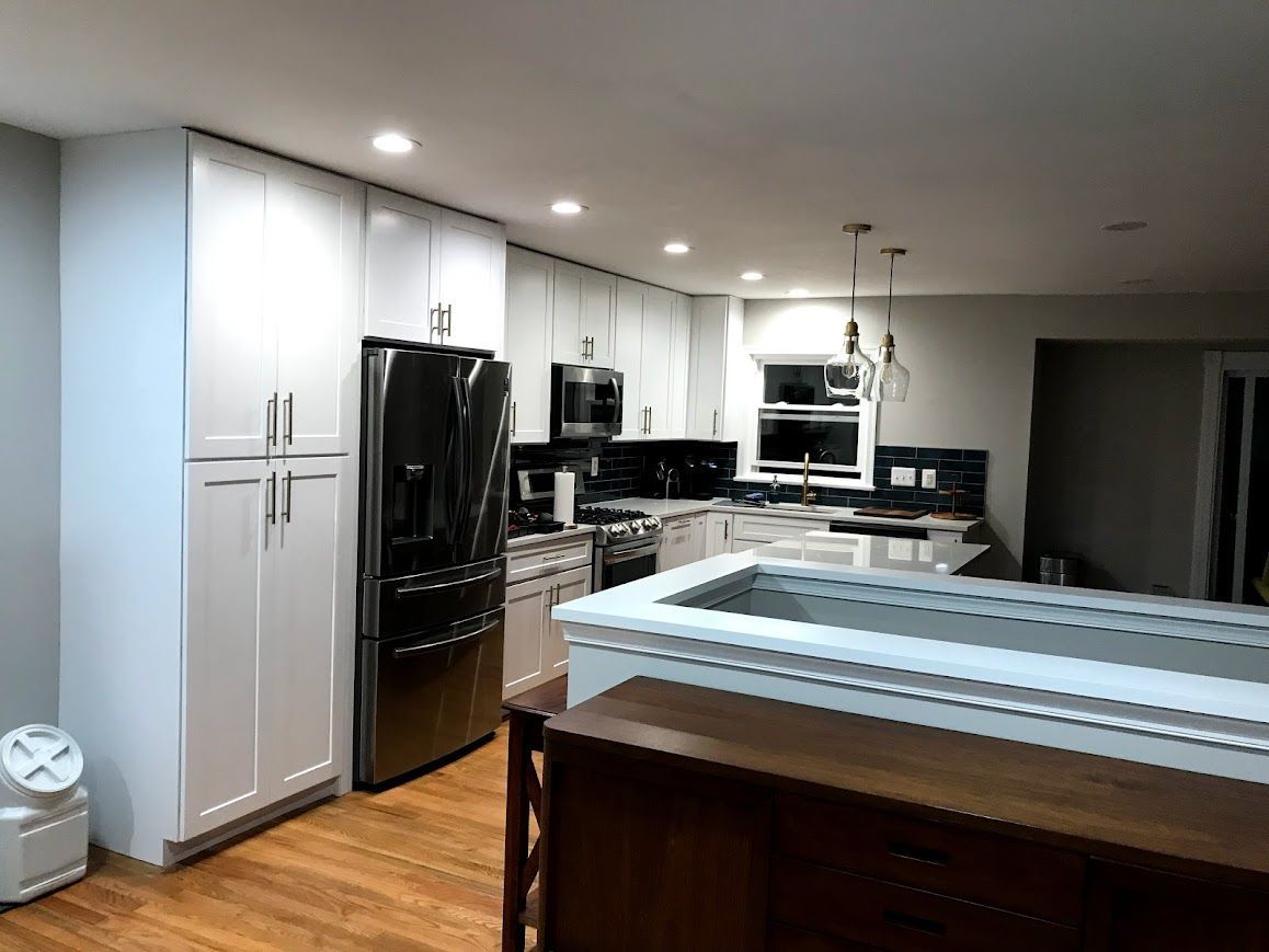 Modern kitchen with white cabinets, stainless steel appliances, and wood floors.
