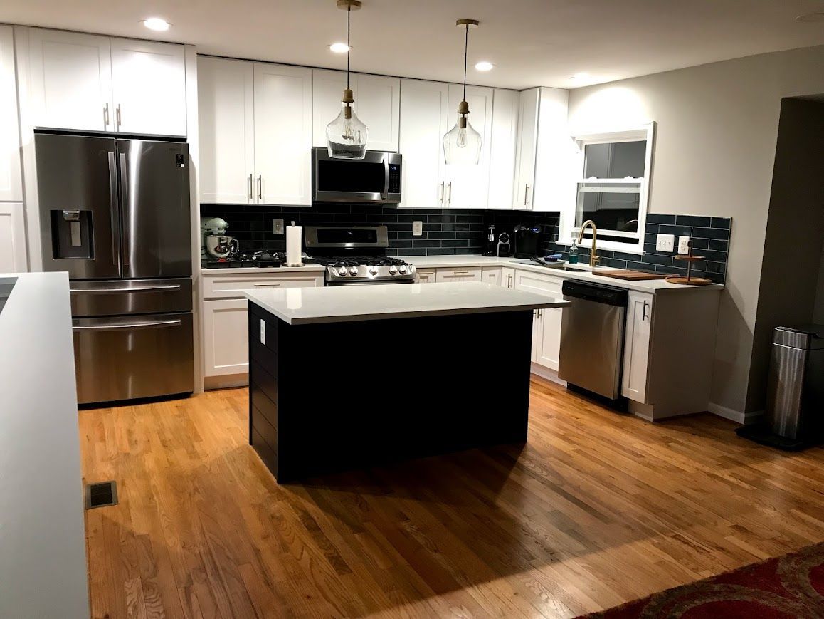 Modern kitchen with white cabinets, stainless steel appliances, and dark island.