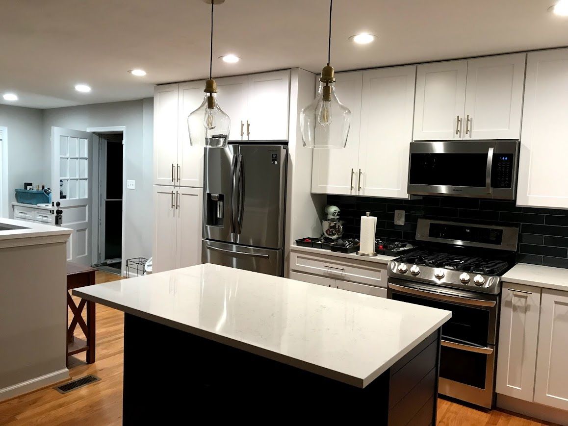 Modern kitchen with white cabinets, stainless steel appliances, and a black island.