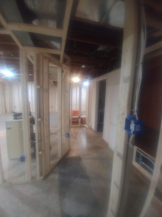 Basement under construction, wooden framing, concrete floor, electrical boxes visible.