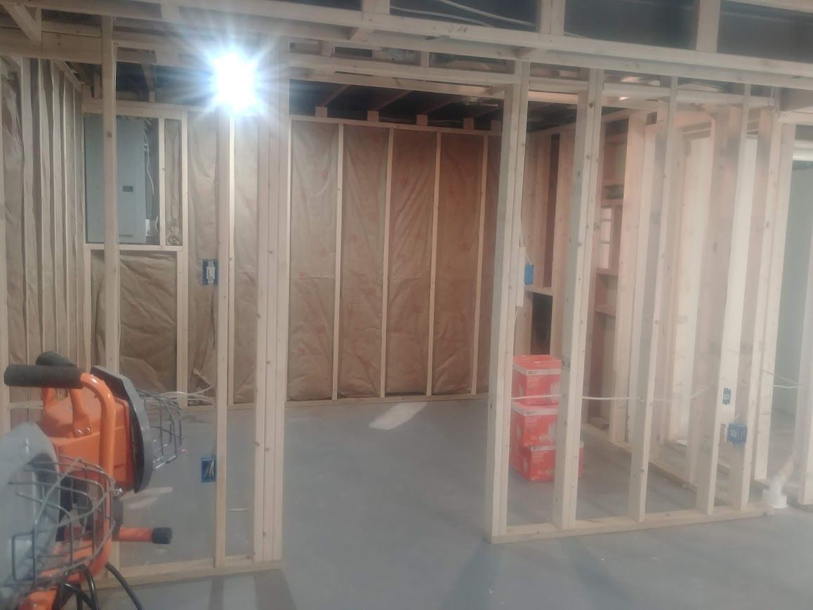 Interior view of a room under construction with wood framing and insulation visible.