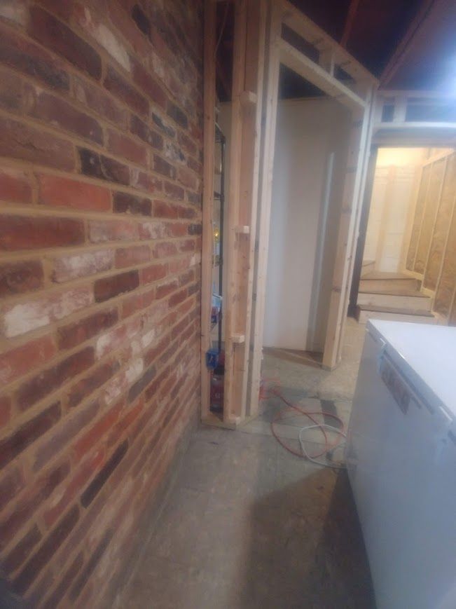Brick wall and wooden door frame in a construction zone. Electrical wires exposed.