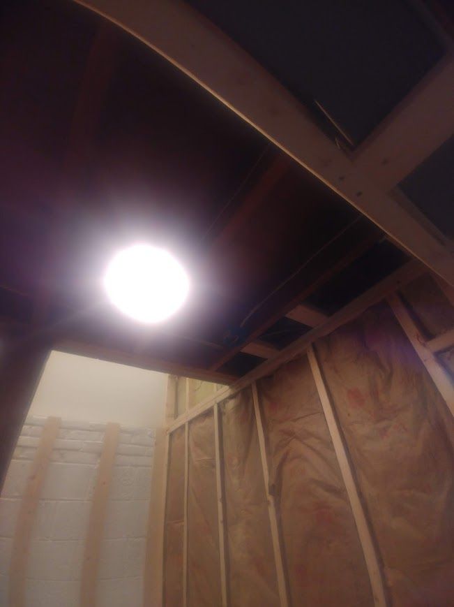 Interior view, construction in progress; light fixture in ceiling, wooden framing and insulation visible.