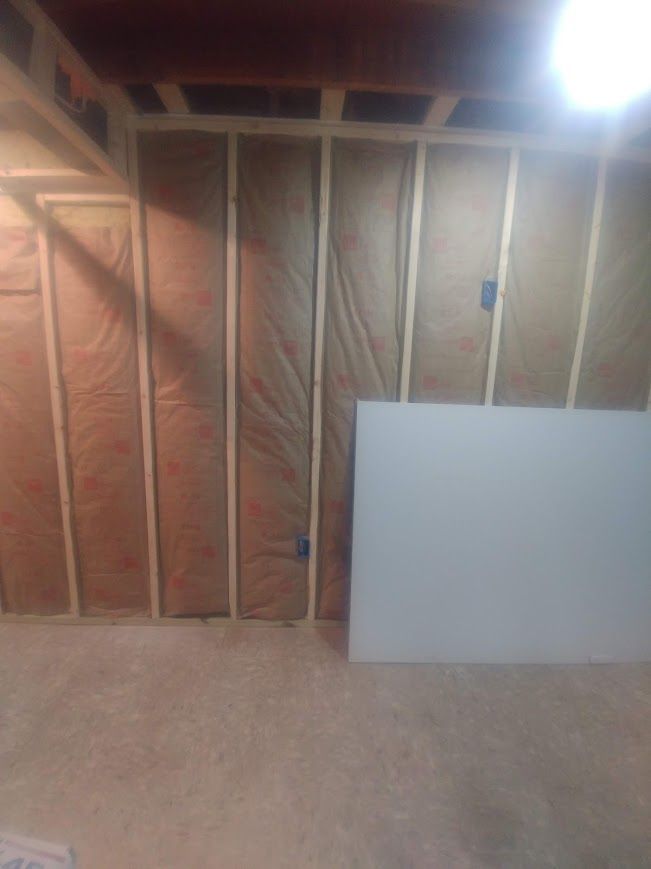 Interior construction with wooden studs, insulation, and drywall.