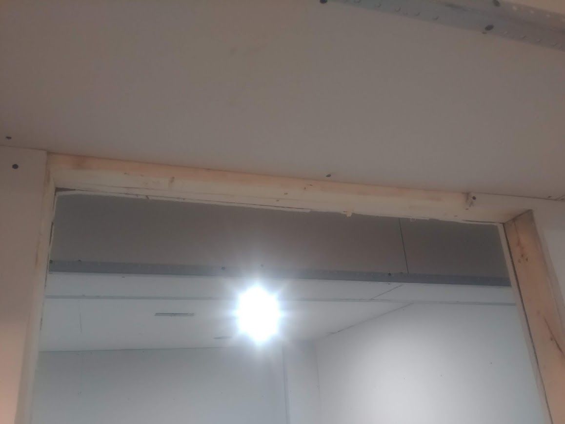Doorway frame partially covered with drywall. A bright light shines through.