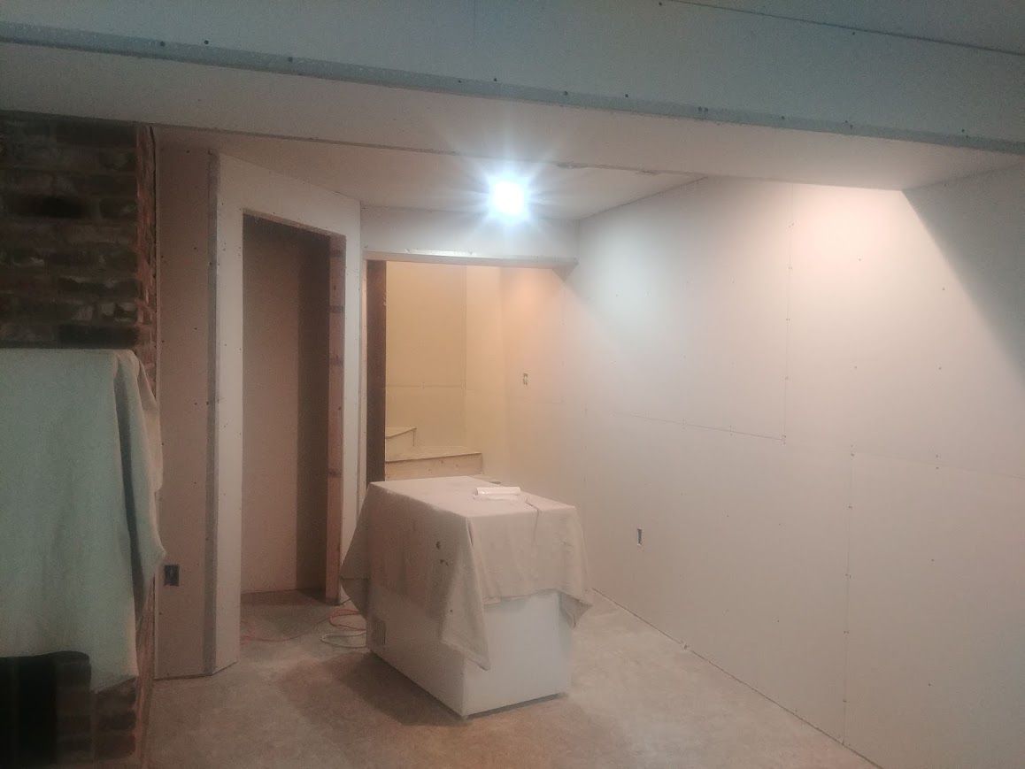 Interior room with white walls, doorway, and covered object.