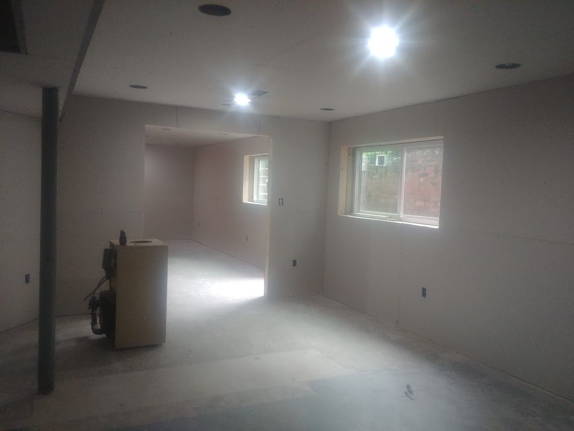 Interior view of a room with unfinished walls and floor; several recessed lights are in the ceiling.