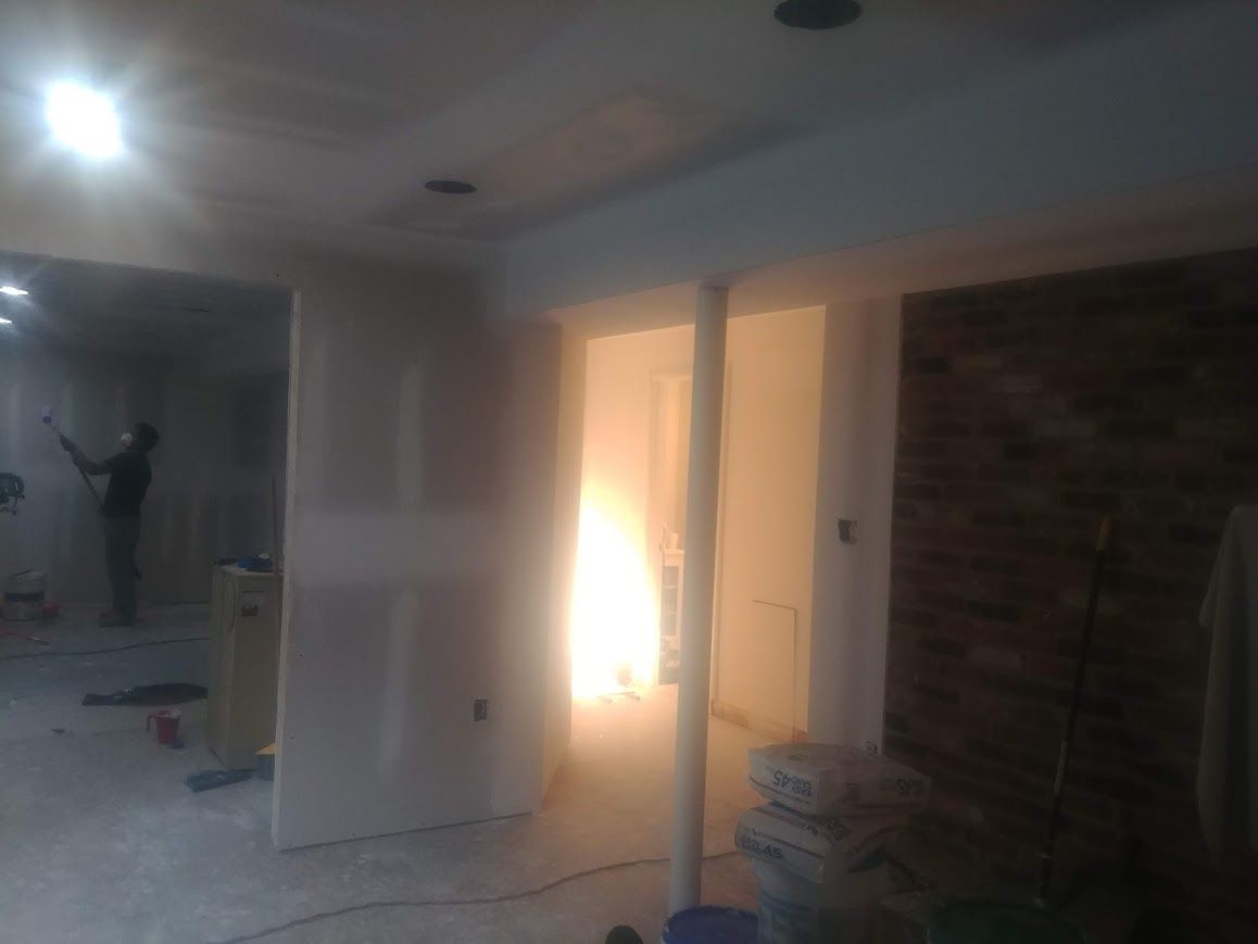 Construction interior with drywall, person working, bright light.