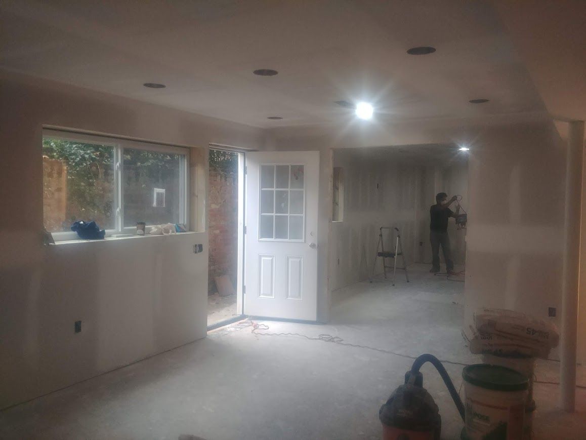 Interior of a room under construction with drywall and door. A person is working in the back.
