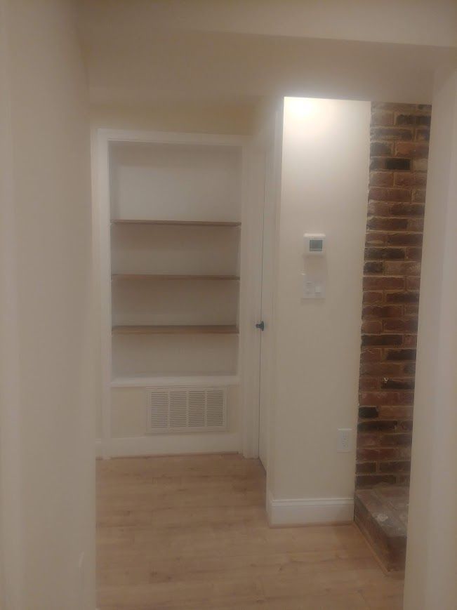 Interior hallway with built-in shelves and brick wall.