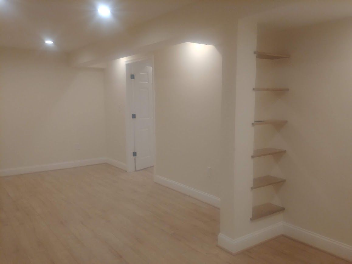 Empty room with beige walls, light wood floor, recessed lighting, and built-in shelves.