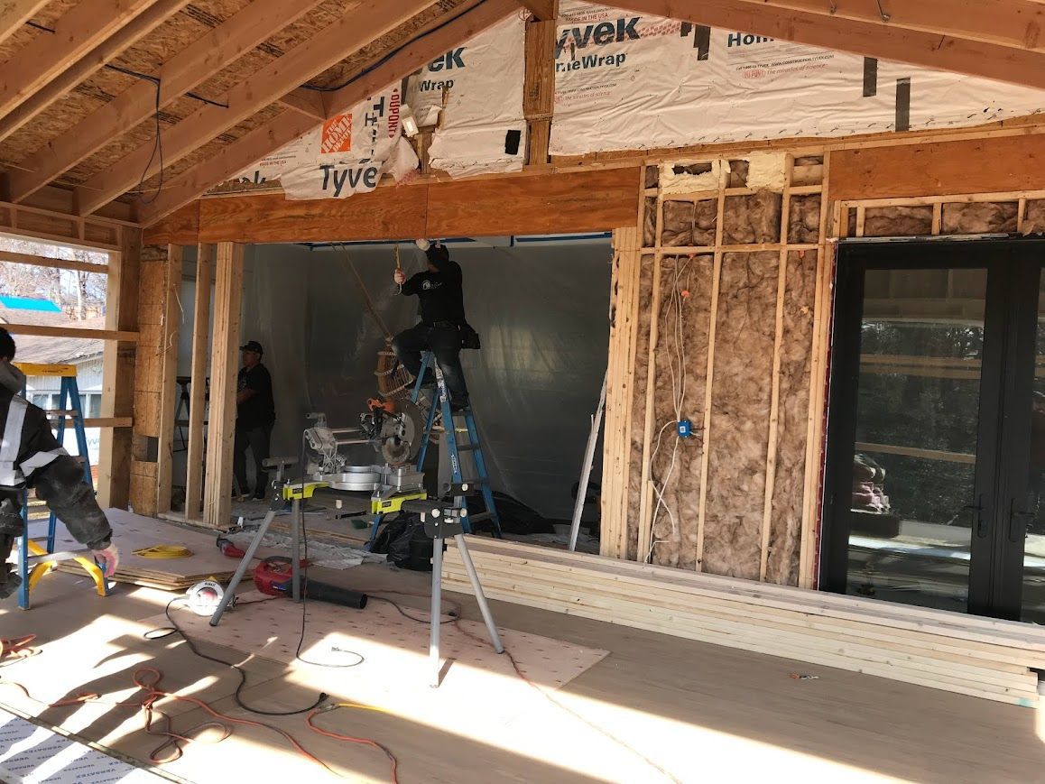 Construction site: workers framing a wall, installing insulation, and using power tools.