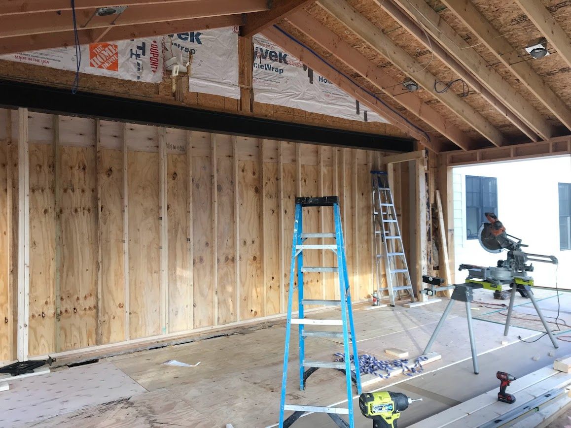 Interior of a room under construction, with wooden framing, a ladder, and tools.