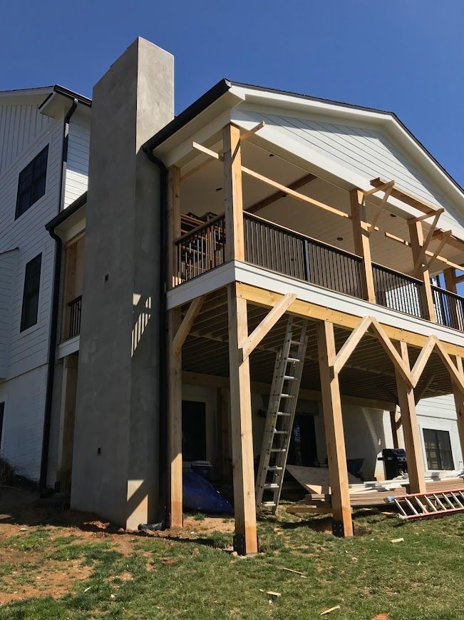 Exterior of a house under construction. A wooden deck and chimney are being built.