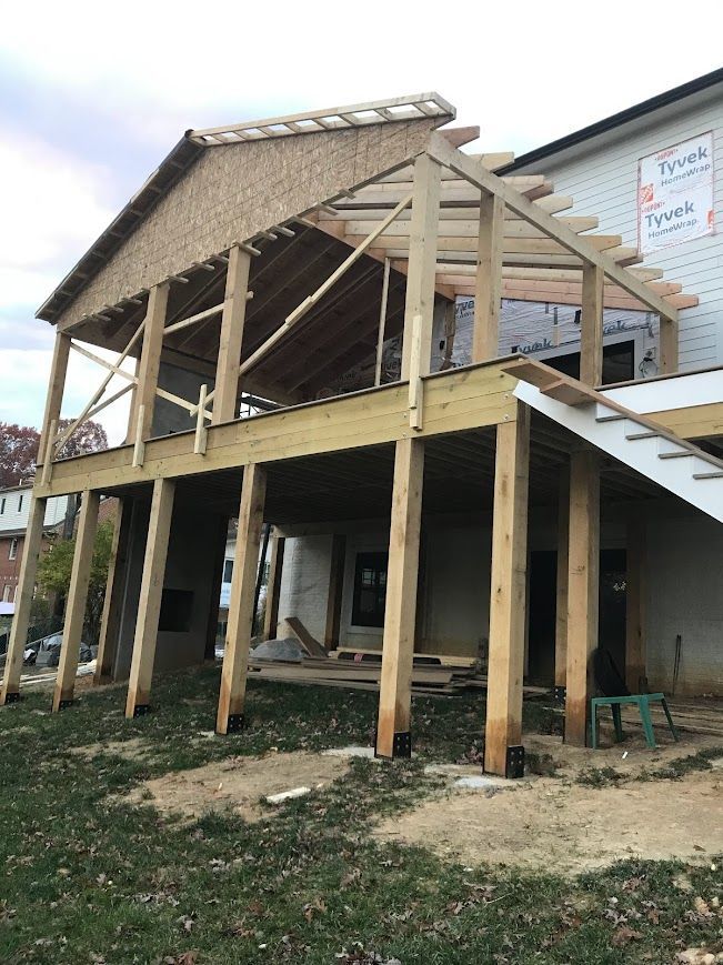 Wooden deck under construction attached to a building, supported by beams.