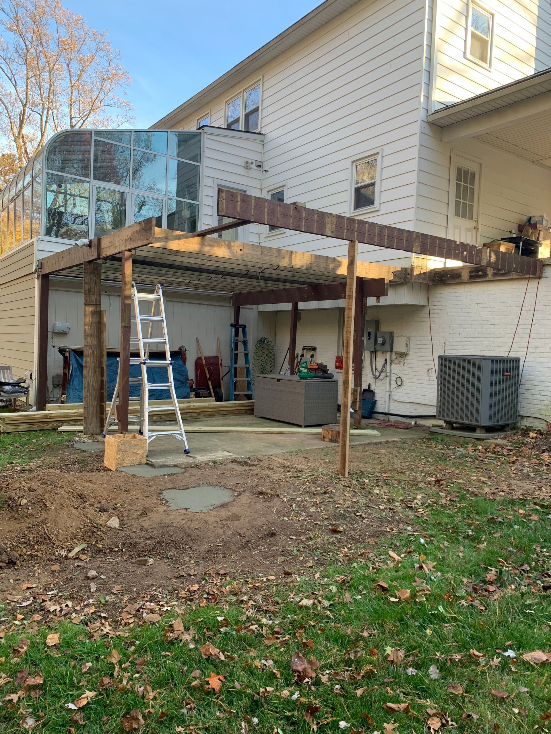 Backyard with a partially built pergola and a ladder. The house is in the background.