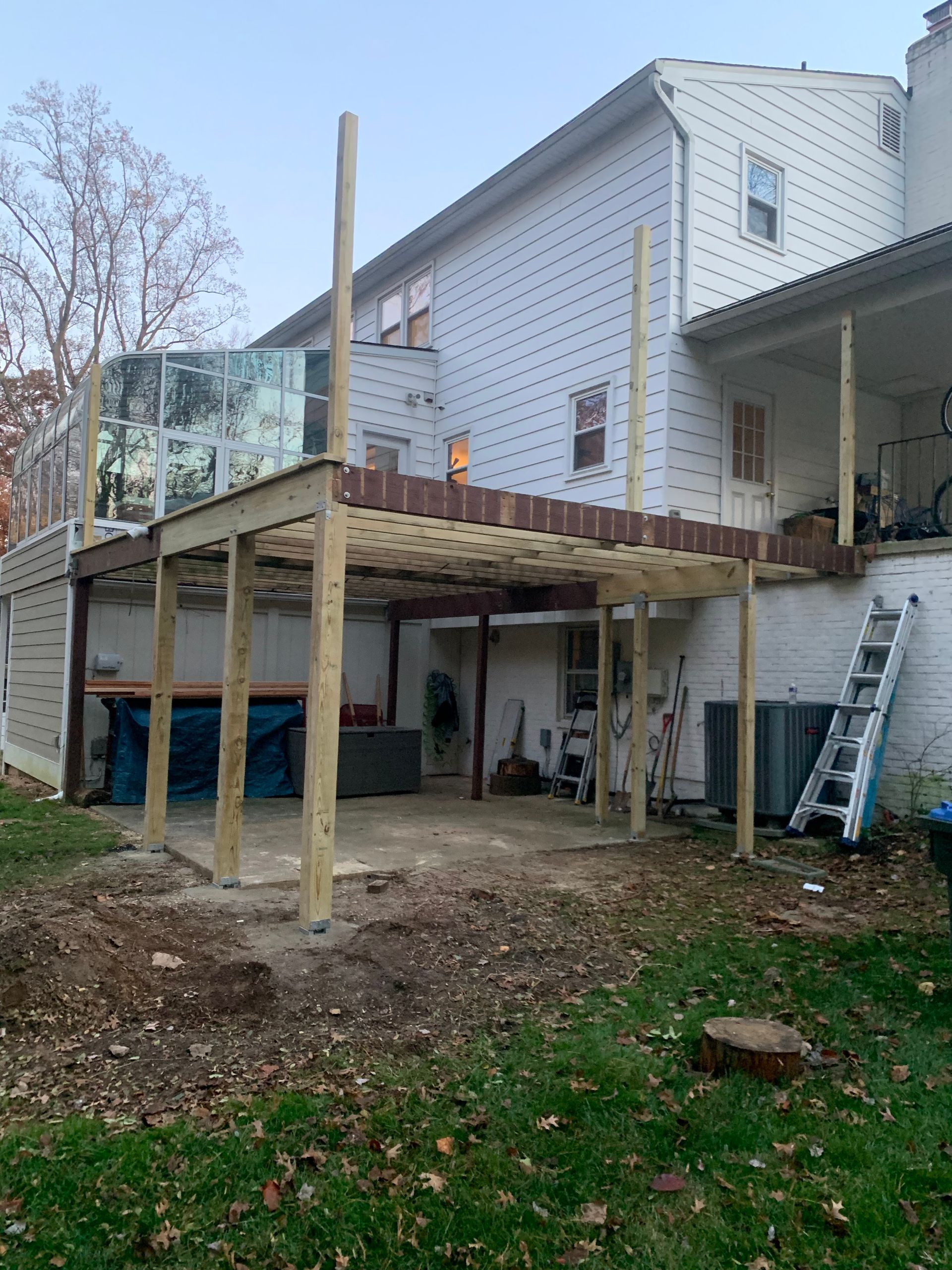 Construction of a two-level wooden deck attached to a white two-story house.