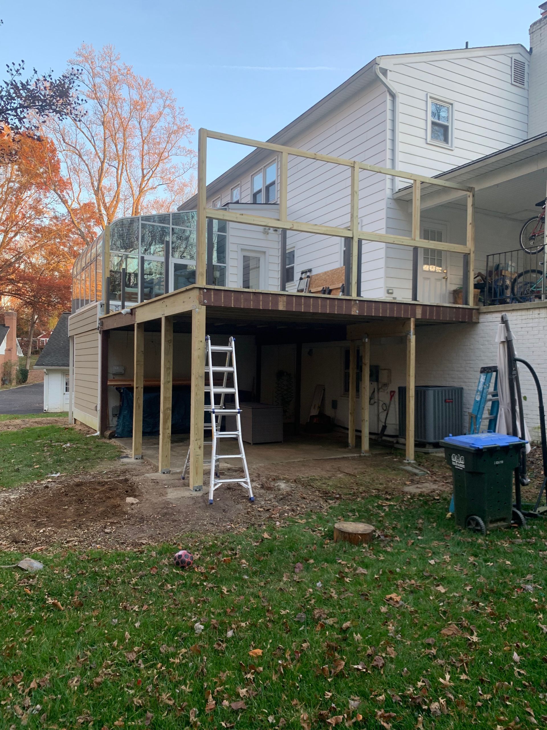 Construction of a wooden deck attached to a two-story white house with a partially built railing.