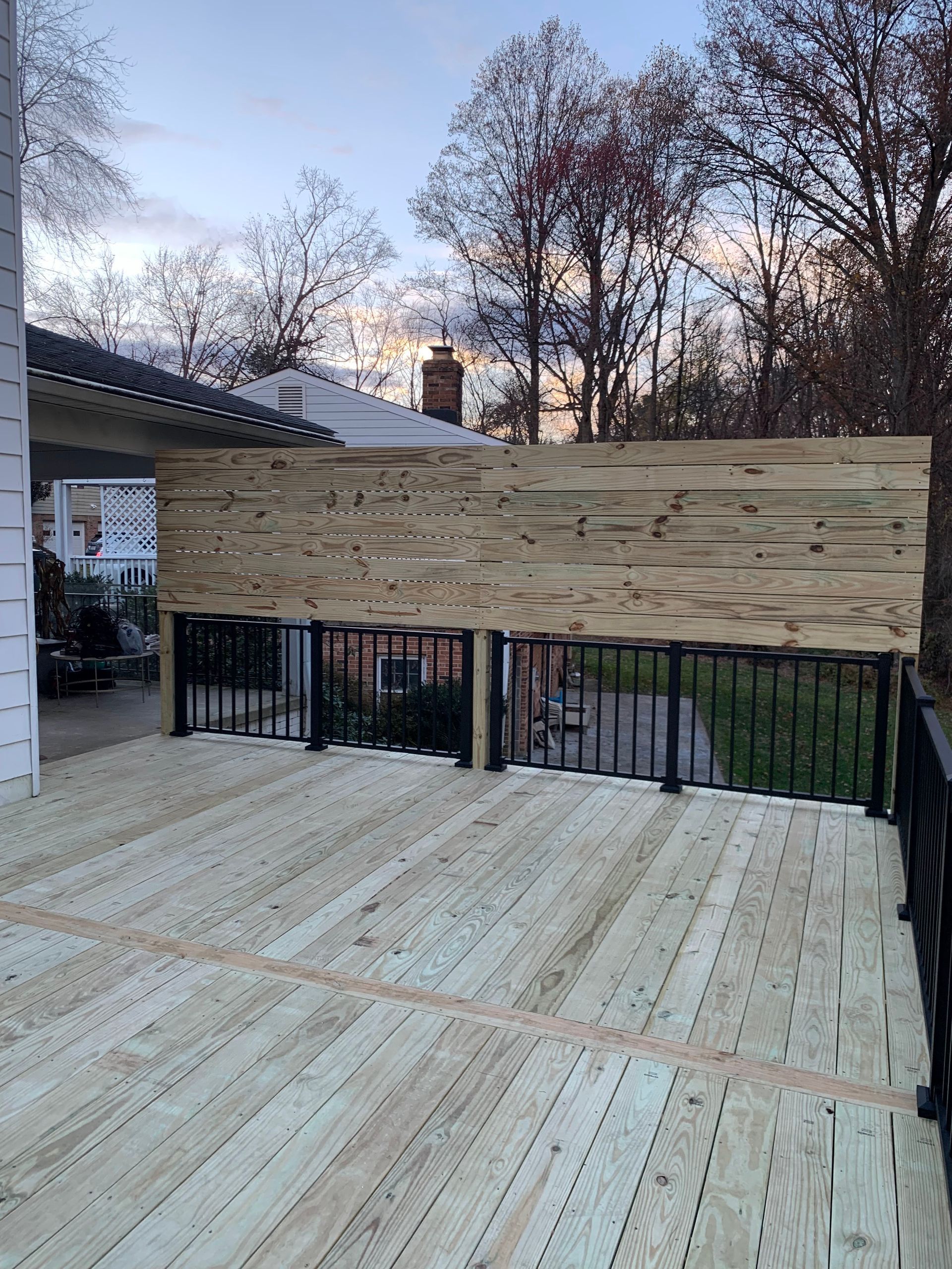 Wooden deck with black railings and a wood privacy screen.
