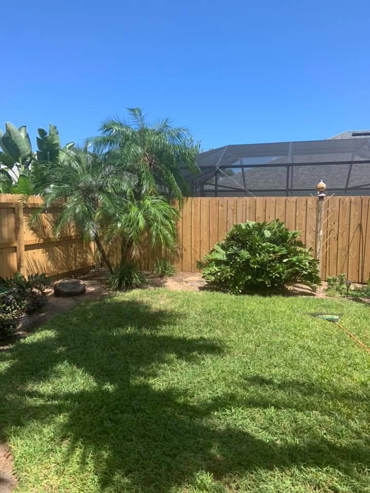 A backyard with a wooden fence and a screened in area.
