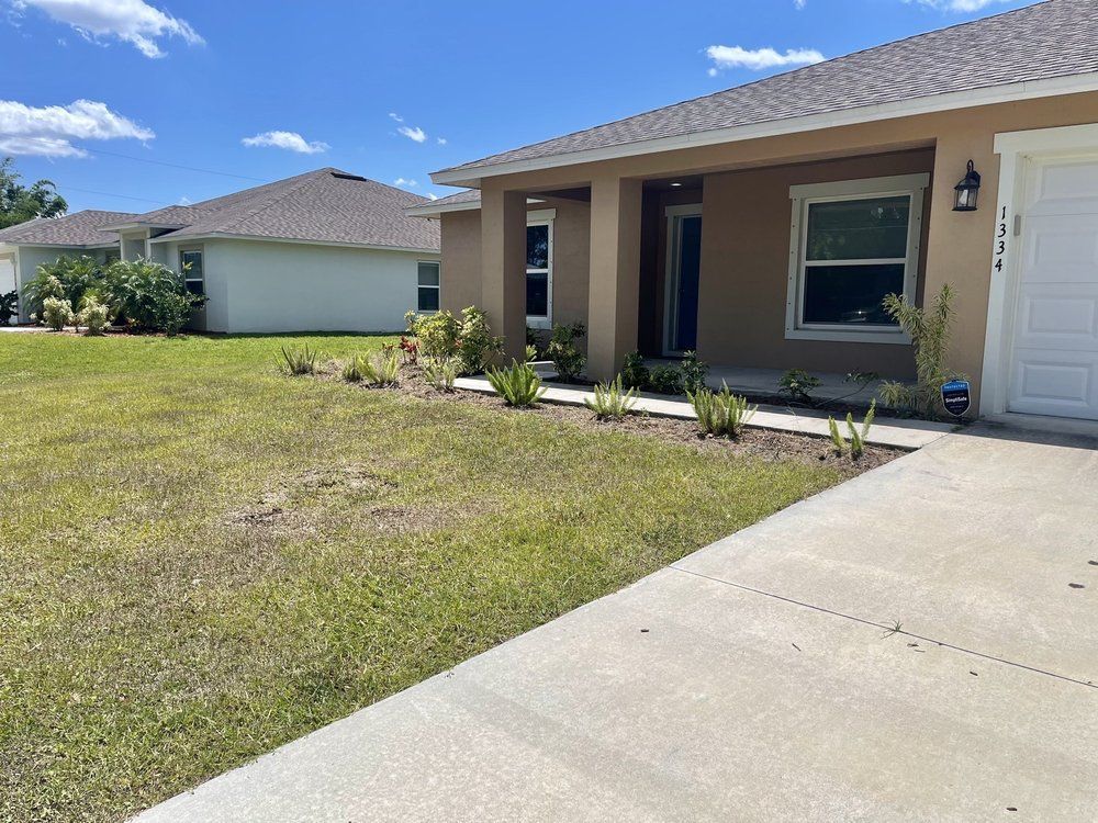 The front of a house with a concrete walkway leading to it.