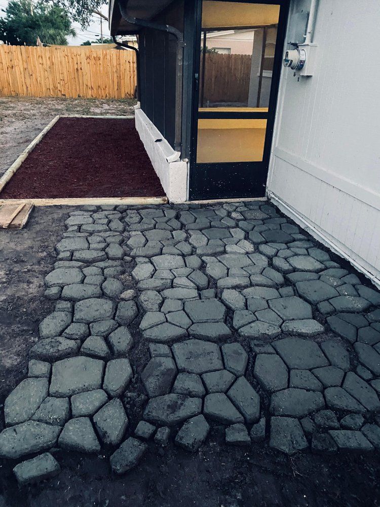 A stone walkway leading to a house with a screen door