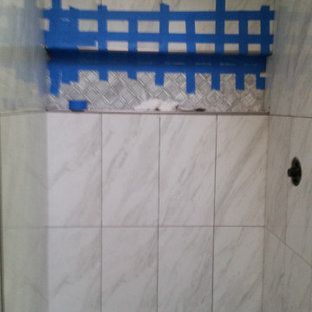 A bathroom with white tiles and blue tape on the wall.