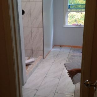 A person is holding a piece of tile in a bathroom.