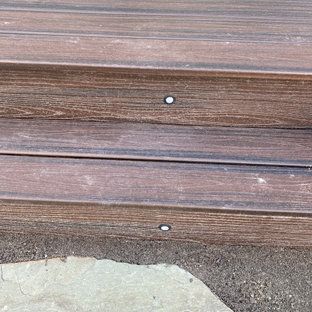 A close up of a wooden staircase with a rock in the background.