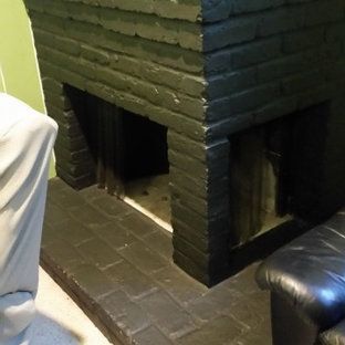 A black brick fireplace in a living room next to a black leather couch.