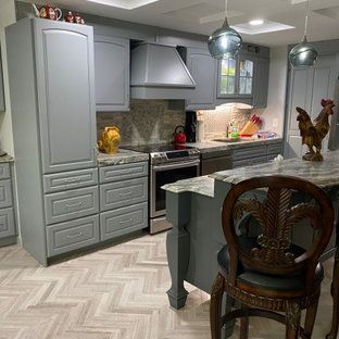 A kitchen with gray cabinets , stainless steel appliances , a stove , and a large island.