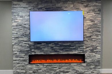 A flat screen tv is mounted on a stone wall above a fireplace.