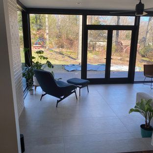 A living room with a chair , ottoman , and large windows.