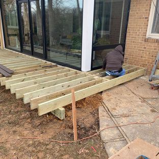 A man is sitting on a wooden deck in front of a house.