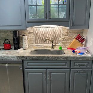 A kitchen with gray cabinets , a sink , and a stainless steel dishwasher.