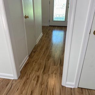 A hallway with hardwood floors and white walls leading to a door.