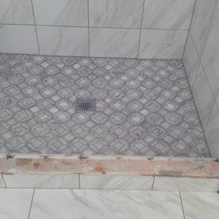 A tiled shower floor with a drain in a bathroom.
