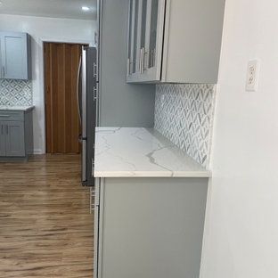 A kitchen with gray cabinets and a white counter top.