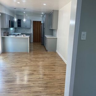 A kitchen with hardwood floors and gray cabinets in a house.