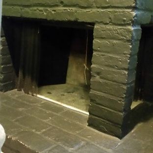 A person is standing in front of a brick wall with a hole in it.