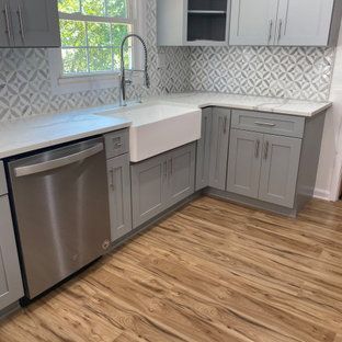 A kitchen with gray cabinets , a stainless steel dishwasher , a sink , and a window.