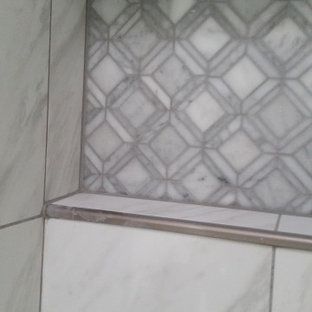 A close up of a tiled wall with a shelf in a bathroom.