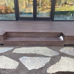 A wooden deck with stairs and a stone walkway in front of a house.