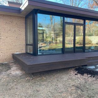 A house with a large window and a wooden deck in front of it.