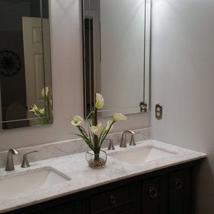 There is a vase of flowers on the counter in the bathroom.