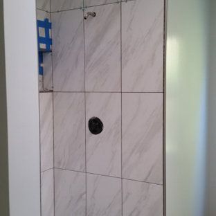 A shower stall with white tiles and a black shower head.