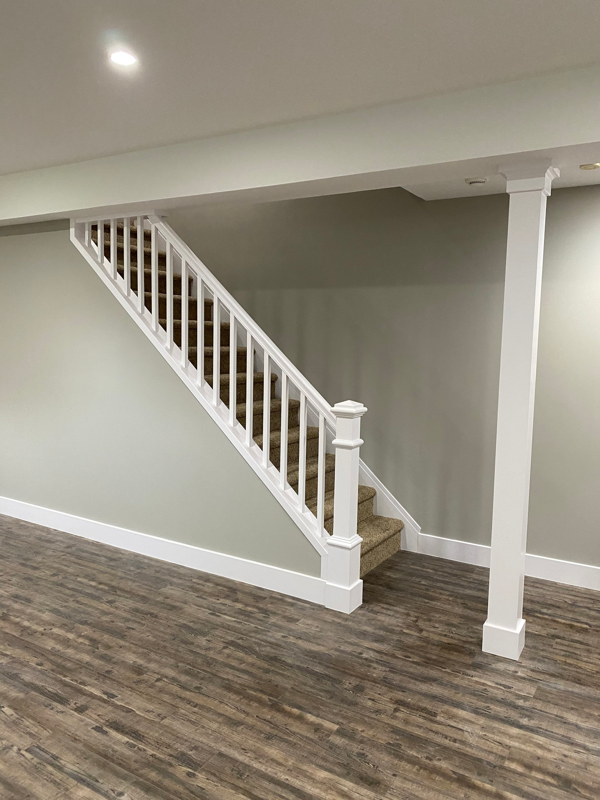There is a staircase in the basement with a white railing.